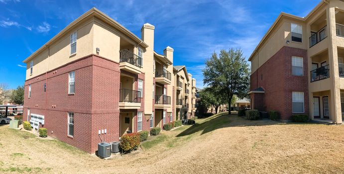 Panorama view modern apartment complex building with steep backyard in Lewisville, Texas, USA. Sunny spring day with cloud blue sky