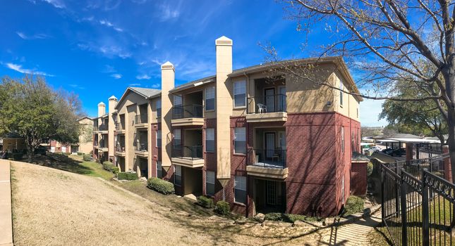 Panorama view modern apartment complex building with steep backyard in Lewisville, Texas, USA. Sunny spring day with cloud blue sky