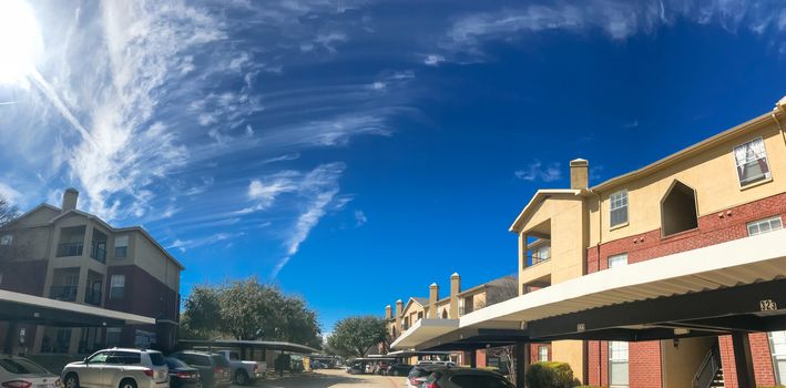 Typical panorama view modern apartment complex building with covered parking in Lewisville, Texas, USA. Sunny spring day with cloud blue sky