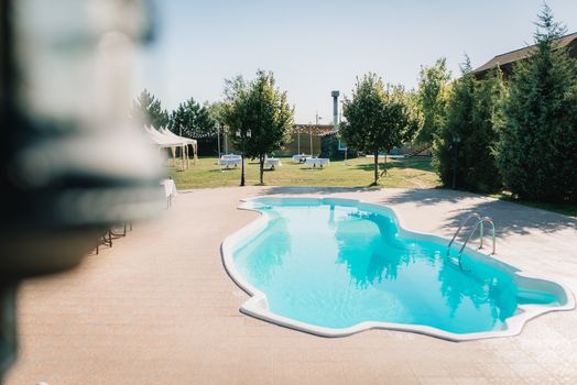 blue outdoor pool in the garden surrounded by coniferous trees