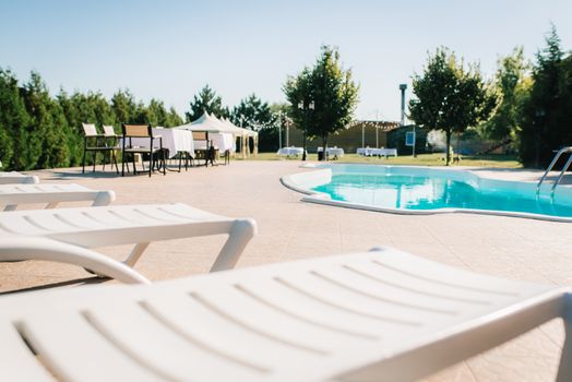 blue outdoor pool in the garden surrounded by coniferous trees