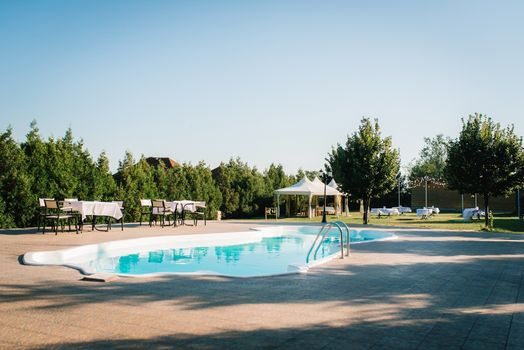 blue outdoor pool in the garden surrounded by coniferous trees