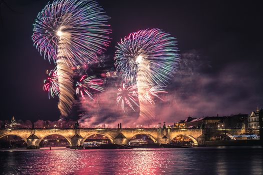 Beautiful fireworks above Charles bridge at night in Prague, historic center, Czech Republic, bautiful reflections in water.