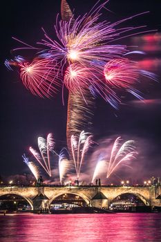 A fireworks show is staged near the historical Charles Bridge in the centre of Prague, with reflections in water.