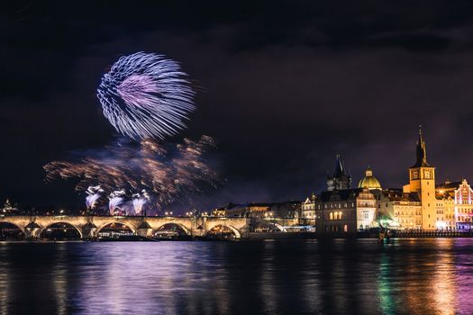 Beautiful fireworks above Charles bridge at night in Prague, historic center, Czech Republic, bautiful reflections in water.