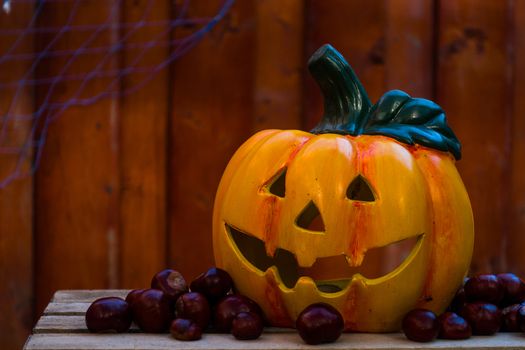 Halloween Pumpkin od wooden background with chestnuts, illuminated by candles, dark red glow, copyspace, holiday concept, decoration