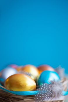 Beautiful Happy Easter holiday greeting banner with easter nest with colored eggs and decorated with ribbons over light wooden background with copy space for text on blue