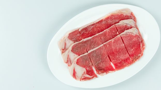 Top view of some raw beef on a plate over white background