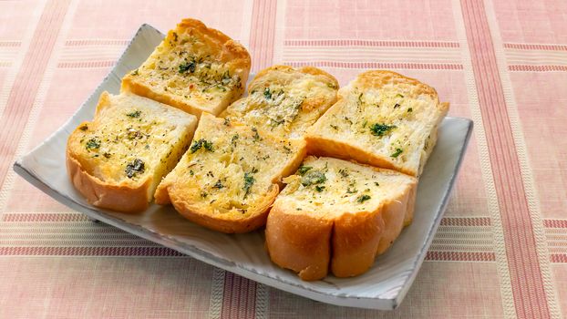 Tasty bread with garlic, cheese and herbs on plate