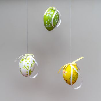 some colorful and decorated Easter eggs hanging by a thread