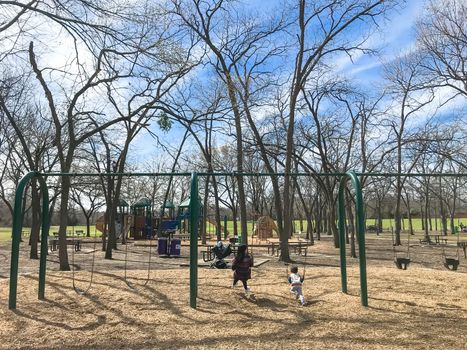 Kids running at colorful playground during wintertime in Lewisville, Texas, USA.