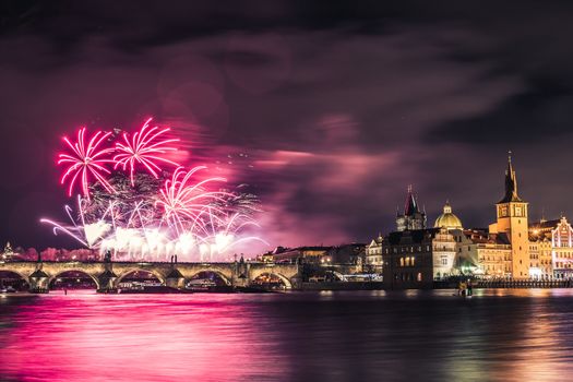 Beautiful fireworks above Charles bridge at night in Prague, historic center, Czech Republic, bautiful reflections in water.