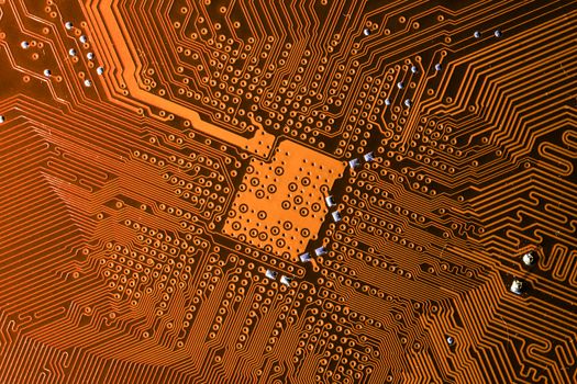 Close up photo of orange printecd circuit board with solder points