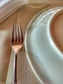 Fork, plate and napkin on tidy linen towel to start dinner, with soft light