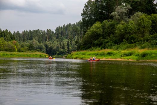 People boating on river Gauja in Latvia, peacefull nature scene. By boat through the river. Boat trip along the Gauja River in Latvia. The Gauja is the longest river in Latvia, which is located only in the territory of Latvia. Length - 452 km.

