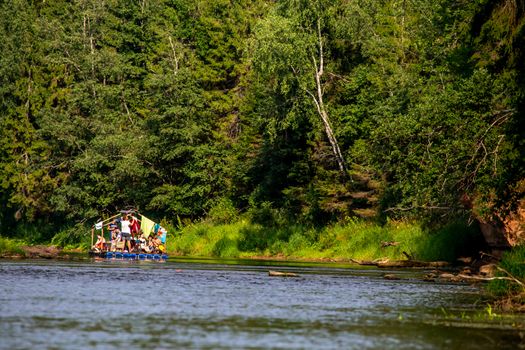 People boating on river Gauja in Latvia, peacefull nature scene. By raft through the river. Raft trip along the Gauja River in Latvia. Boating on river. The Gauja is the longest river in Latvia, which is located only in the territory of Latvia. Length - 452 km.


