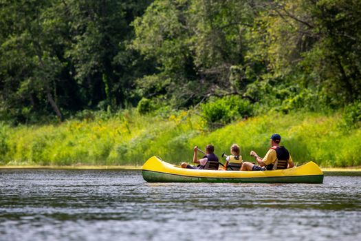 Family in yellow kayak drives on the river. People boating on river Gauja in Latvia, peacefull nature scene. By boat through the river. Boat trip along the Gauja River in Latvia. The Gauja is the longest river in Latvia, which is located only in the territory of Latvia. Length - 452 km.

