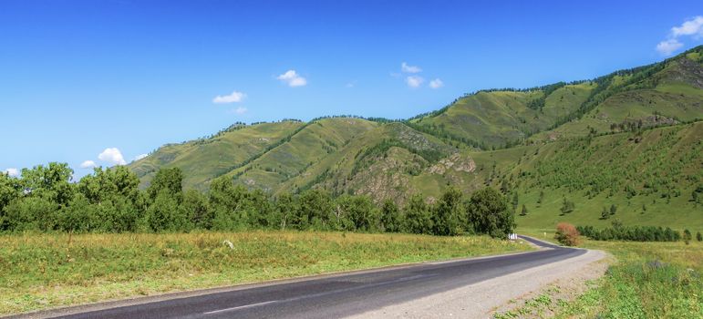 The road among the mountains in summer and the blue sky with clouds