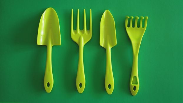 Set of green garden tools on green background - top view