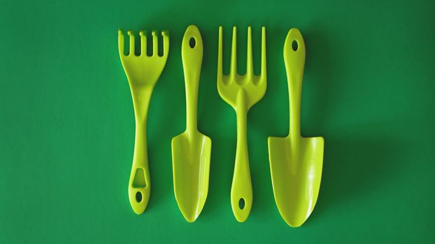 Set of green garden tools on green background - top view