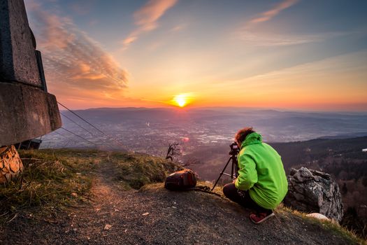 Photographer taking pictures of the sunrise on the top of the mountain
