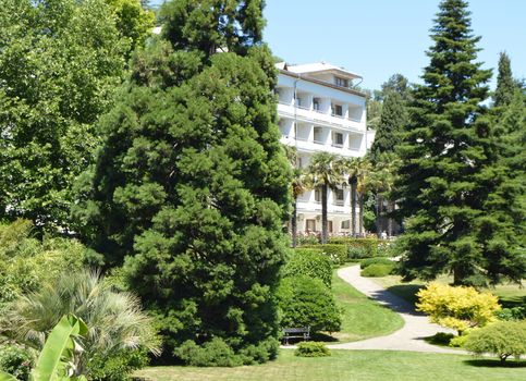 White building, standing in the middle of the trees and a beautiful Park area for private recreation.