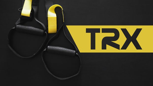 Black and yellow strap functional training equipment on grey background. Sport accessories. Fitness and Gym workout items for Healthy. Banner TRX