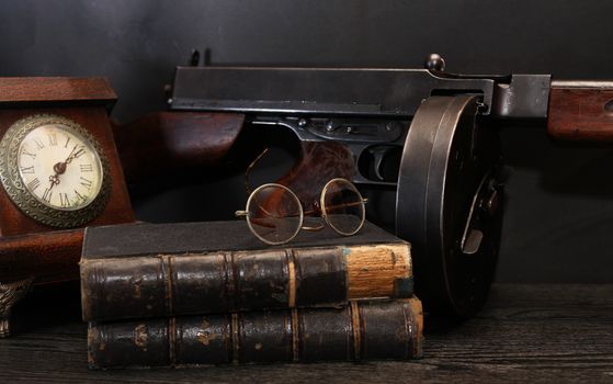 Vintage still life with clock and old USA submachine gun on dark background