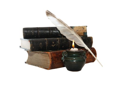 Vintage still life with quill pen and old books near lighting candle