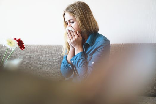 Spring cold or allergies. A young attractive girl is allergic to flowers, uses a napkin at home