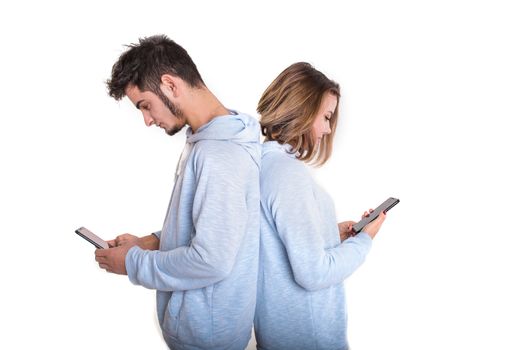 Unhappy couple backwards with their mobile phones typing isolated on white