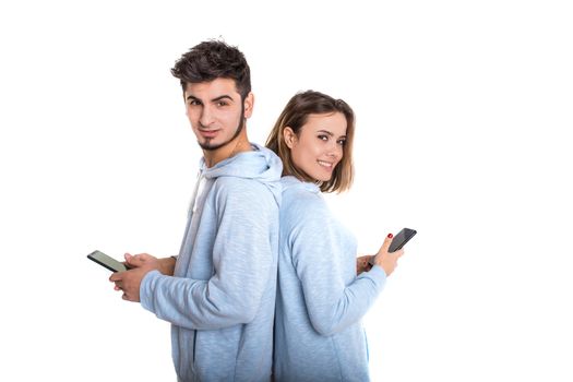 Smiling couple backwards with their mobile phones isolated on white background