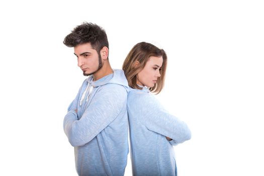 Unhappy young man and woman are standing back each other and not speaking, isolated on white