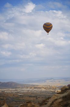 Hot air balloon flying over the rocky land. Cappadocia, Turkey