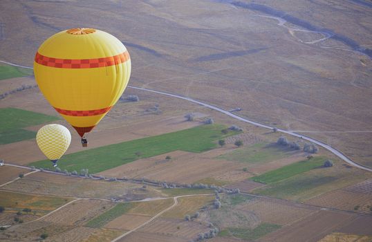 Two yellow air balloons flying over the land