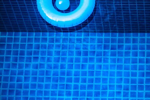 Aerial view of inflatable ring toy in swimming pool water from above, vacation concept background