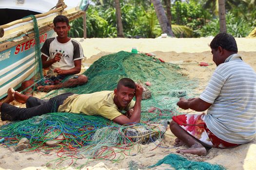 Kalutara, Sri Lanka - April 10, 2011: Three fishermen with fishing nets on the beach of Kalutara in Sri Lanka.