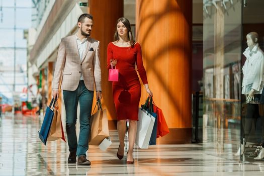 Happy beautiful young couple walking in mall holding shopping bags