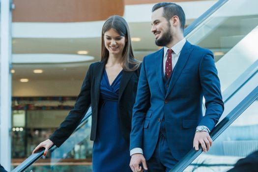 Business couple on escalator talking and smiling