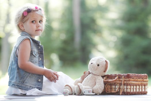 Pretty girl playing with teddy bear outdoors