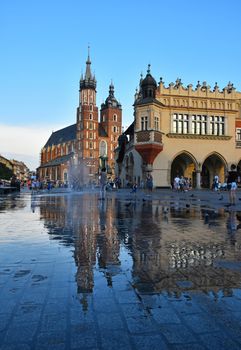 Low angle view of Main Market Square with town hall and Church of Our Lady Assumed into Heaven (Saint Mary Church after rain in Krakow, Poland