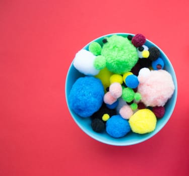 Blue bowl of fluffy colorful ball on red background