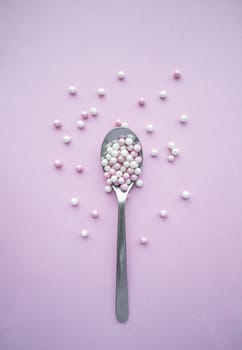 Stainsteel spoon with small balls on pink background