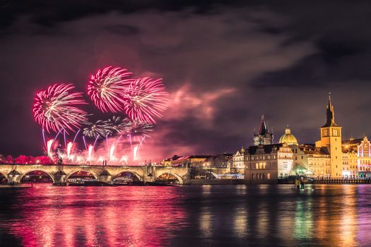 Beautiful fireworks above Charles bridge at night in Prague, historic center, Czech Republic, bautiful reflections in water.