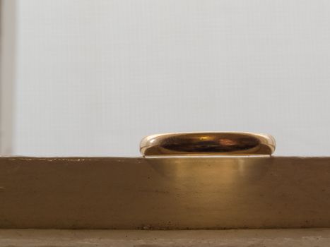 Only an old wedding ring, in gold, on a white dresser.