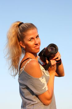 Blonde girl with camera. Smiling and looking in the camera.