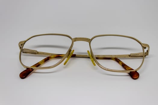 old glasses closeup with gold frame. product photo shoot with white background.