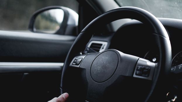 Interior view of car with black salon. Close-up Of A Man Hands Holding Steering Wheel While Driving Car