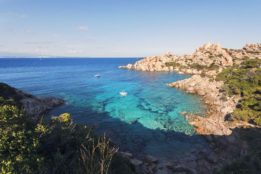 panoramic view of a creek with anchored boats. Vegetation and rocks surround it, scenic place for vacationers and summer holidays, bright colors. Capo Testa, Santa Teresa di Gallura, Sardinia, Italy