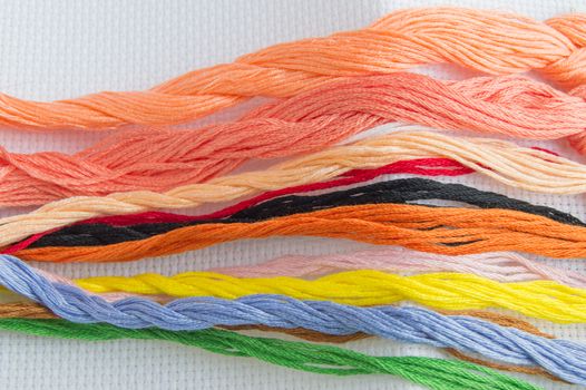 Bright colorful thread for embroidery thread on canvas. Handmade accessories on white background. Place for text, top view.
